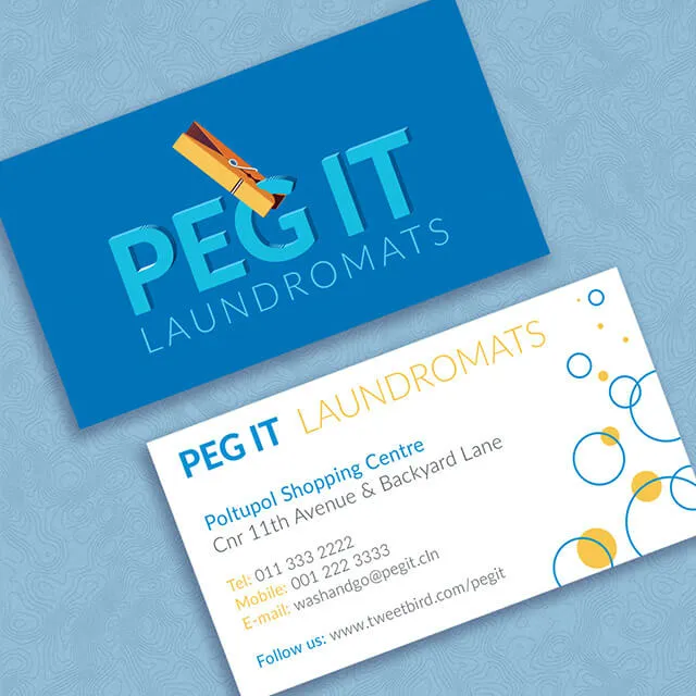 Two Peg It business cards on a pale blue ground. The front is deep blue with PEG IT set in heavy pale blue capitals, a yellow clothes peg clipped diagonally over the G and I, and LAUNDROMATS spaced out beneath; the back is white, with the address and contact details in blue and yellow beside a scatter of blue rings and yellow dots.